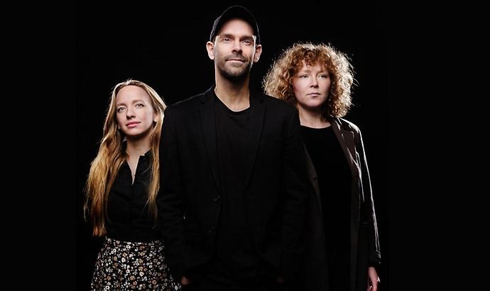 Tre personer framför mörk bakgrund