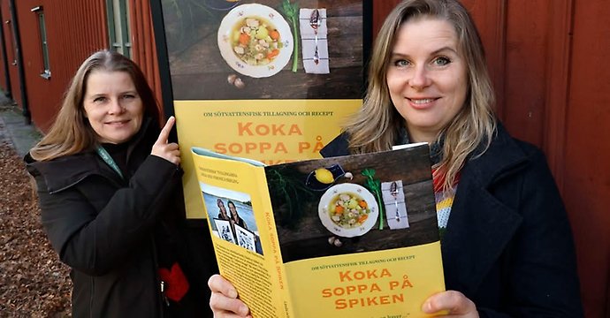 Två kvinnor som håller upp en bok