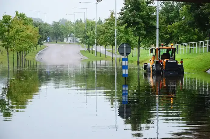 översvämmad väg och ett fordon som passerar genom vattenmassorna